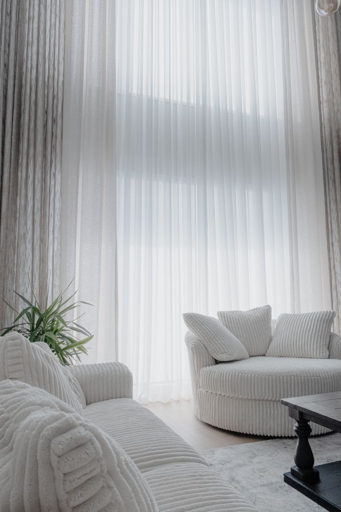 services-img-04 A serene living room with white furniture and tall sheer curtains, exuding modern elegance.