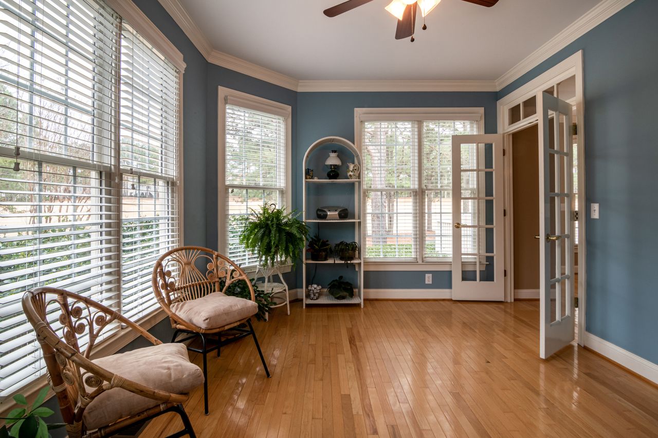 our-services-01 Bright and inviting room with wooden flooring, rattan chairs, and natural lighting through large windows.