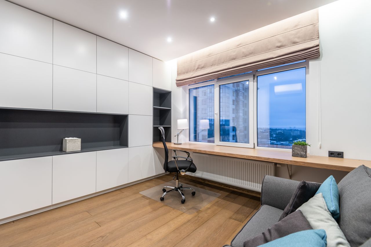 why-choose-us-img Armchair near wooden shelf between white cupboards and comfortable sofa with pillow in light stylish room with window at home
