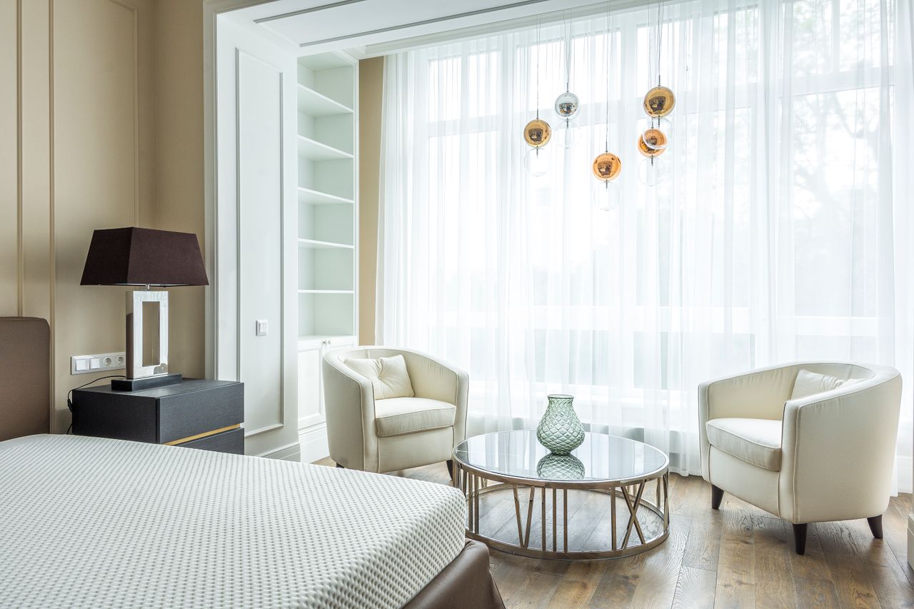 cta-image A bright and contemporary bedroom featuring stylish seating, a large window, and minimalistic decor.